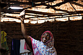 A woman smiling as she turns on the new solar light in her mud hut, Tanzania, East Africa, Africa