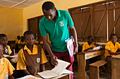 Ein männlicher Lehrer unterrichtet ein Klassenzimmer von Kindern an einer Grundschule in Ghana, Westafrika, Afrika