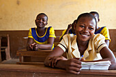 Ein Porträt eines Schulmädchens, das während einer Lektion in ihrem Klassenzimmer, Ghana, Westafrika, Afrika lächelt