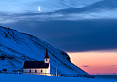 Flutlichtkirche in der Morgendämmerung gegen schneebedeckte Berge, Winter, in der Nähe von Vik, Südisland, Polargebiete