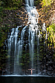 Junge Frau, die in Farofa-Wasserfall in Serra do Cipo National Park, MG, Brasilien aufwirft