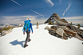 Photograph with rear view of male backpacker hiking to Needle Peak in winter, Hope, British Columbia, Canada