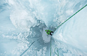 Fotografie des abenteuerlichen Mannes, der aus Glazial- Moulin, Coleman-Gletscher, Berg Baker, Washington State, USA heraus klettert.