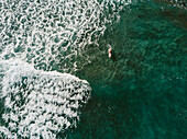 Aerial view of female surfer surfing in crystal clear water, Tenerife, Canary Islands, Spain