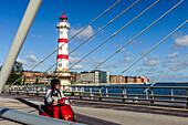 Rot weißer Leuchtturm im sarniertem Hafengebiet, roter Motorroller im Vordergrund auf einer Brücke, Malmö Südschweden, Schweden
