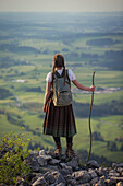 Young woman in traditional costume enjoying the view over the Allgaeu from the Falkenstein, Pfronten, Bavaria, Germany