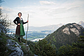 Junge Frau in Tracht steht auf einem Felsen auf dem Falkenstein im Allgäu, Pfronten, Bayern, Deutschland