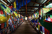 Prayer flags hanging in wooden footbridge