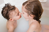 Caucasian boy and girl rubbing noses in bathtub