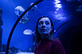 Caucasian woman admiring fish in aquarium
