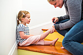 Caucasian mother painting toenails of daughter on staircase