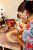 Mixed race woman shaping clay mask in art studio