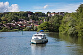 Le Boat Magnifique houseboat during cruise on Petit Saône river with town and Château Ray-sur-Saône castle behind, Ray-sur-Saône, Haute-Saône, Bourgogne-Franche-Comté, France