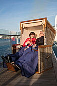 Couple enjoy drinks in Strandkorb basket on Deck 14 of cruise ship Mein Schiff 6 (TUI Cruises), near Rønne, Bornholm, Denmark