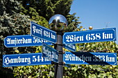 Distance signs in traditional Bavarian lettering in gardens of Hotel Brunnenhof, Weibersbrunn, Spessart-Mainland, Franconia, Bavaria, Germany