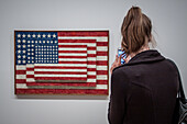 tourist taking a photo with her smartphone of the painting by the american artist jasper johns entitled three flags, whitney museum of american art, meatpacking district, manhattan, new york city, state of new york, united states, usa
