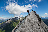 mountaineer doing a relay at the summit of a point on the arete a marion, pointes de la blonniere, the aravis massif in the background, aravis mountain range (74), france