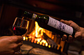 Bottle and glass of wine in front of fireplace, San Romerio Alp, Brusio, Poschiavo Valley, Canton of Graubunden, Switzerland, Europe