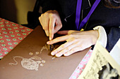 Crafts. Ornamental engraving. Young woman working on an engraving.