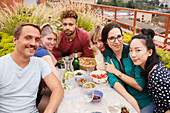 Portrait of happy male and female friends sitting at outdoor table at patio