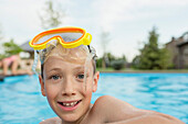 Portrait of smiling shirtless boy with swimming goggles in pool