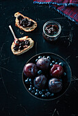 Directly above shot of fruits with open faced sandwich and preserves on granite