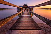 Auf dem Steg zum Bootshaus bei farbenfrohem Sonnenuntergang, Stegen, Bayern, Deutschland