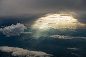 sunrays pierce through a hole in the clouds and light up the hills of the northitalien alps, aerial shot, northwest of Milan, Italy