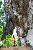 Frau, Touristin steht unterhalb einer beeindruckenden Felswand auf einer Wanderung durch den Nationalpark Topes de Colantes, wandern, beliebter Tagesausflug von Trinidad, Naturverbundenheit, Einsamkeit, Familienreise nach Kuba, Auszeit, Elternzeit, Urlaub