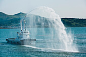 Als Willkommensgeste spritzt ein Schlepper Wasser für Expeditions-Kreuzfahrtschiff MS Bremen (Hapag-Lloyd Cruises), Funagawa, Oka, Akita, Japan, Asien