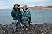 Two elders stand along the shore in modern and traditional clothing, Ulukhaktok (also Holman), Victoria Island, Northwest Territories, Canada, North America