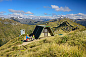 Man and woman sitting at shelter on Kepler Track, Kepler Track, Great Walks, Fiordland National Park, UNESCO Welterbe Te Wahipounamu, Southland, South island, New Zealand