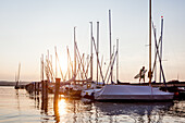 Menschen auf dem Steg am Sonnenuntergang am Ammersee, Bayern, Deutschland, Europa