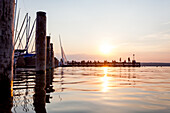 Menschen auf dem Steg am Sonnenuntergang am Ammersee, Bayern, Deutschland, Europa