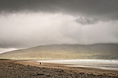 einsame Spaziergängerin im Regen am Keel Strand, Achill Insel, Grafschaft Mayo, Irland, Wild Atlantic Way, Europa