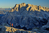 Man and woman hiking looking towards Lavarella, from Lagazuoi, Dolomites, UNESCO World Heritage Site Dolomites, Venetia, Italy