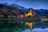Beleuchtete Kirche von Sulden spiegelt sich in See mit Ortler im Hintergrund, Sulden, Ortlergruppe, Südtirol, Italien
