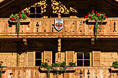 Ein Wohnhaus aus Holz mit Balkonen, Geranien und einem Tirol-Wappen von der Sonne angestrahlt, Ginzling, Zillertal, Tirol, Österreich