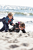 Kids playing at the beach in winter on Baltic Sea, Kellenhusen,  Schleswig Holstein, Germany