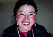 Portrait of a smiling tibetan nomad woman with her cheeks reddened by the harsh weather, Qinghai province, Tsekhog, China.