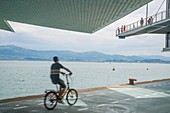 Mann beim Fahrradfahren und Blick auf die Bucht vom Botin Center. Santander, Spanien.