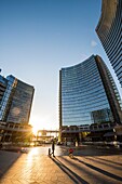 Milan, Lombardy, Italy. People walking in Gae Aulenti square in the new Porta Nuova business district at sunset.