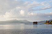 FRENCH POLYNESIA, Raiatea Island. A view of the coastline of Raiatea Island. An abandoned pearl farm hut can be seen in the distance.