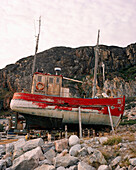 GREENLAND, Ilulissat, Disco Bay, ruined fishing boat in front of rock formation