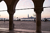 ITALY, Venice.  A view of the column's of Doge's Palace at Piazza San Marco. The island of San Giorgio Maggiore can be seen in the distance, dominated by the tower and dome of the Church of San Giorgio Maggiore.