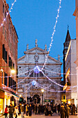 ITALY, Venice. Christmas decorations hangs over Campo San Moise along Calle Larga XXII Marzo. The Chiesa di San Moise is in the center and the front of the Hotel Bauer is on the right.