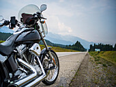 A motorcycle parked on the side of a highway with a view of the mountains in the distance; Spillmacheen, British Columbia, Canada