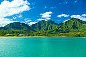 Stunning turquoise ocean water and the rugged green mountains on the island of Kauai; Hanalei, Kauai, Hawaii, United States of America