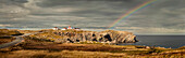 A rainbow across the storm clouds and over the Atlantic ocean and coastline of Newfoundland; Newfoundland, Canada