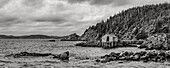 Black and white image of the rocky Atlantic coastline with a dock and boat house; Newfoundland, Canada